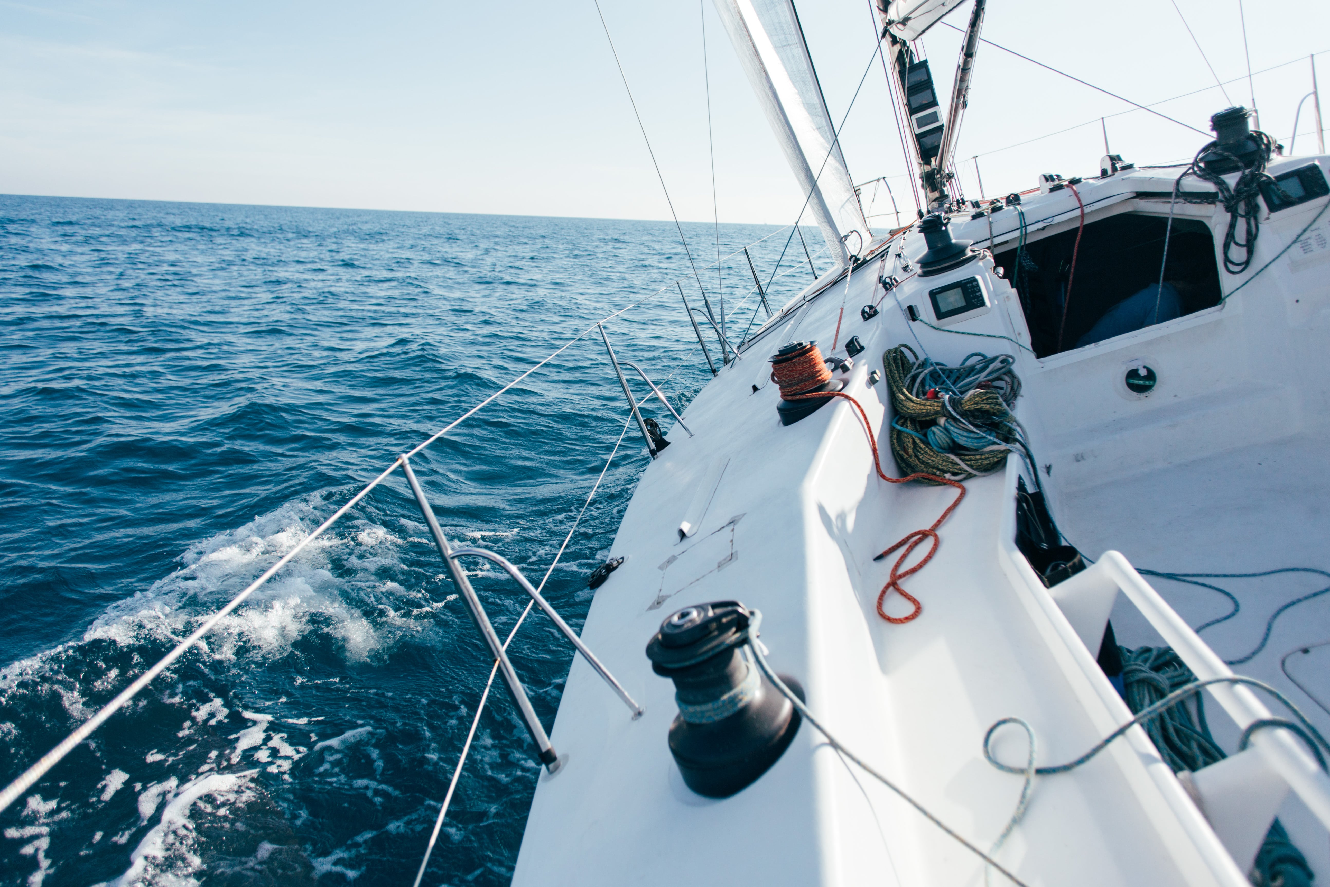 deck of professional sailboat or racing yacht during competition on sunny and windy summer day moving fast through waves and water with spinnaker up